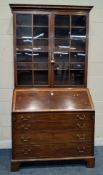 A GEORGIAN MAHOGANY AND CROSS-BANDED BUREAU BOOKCASE, the double glass doors enclosing three