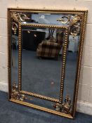 A GILT RESIN BEVELLED EDGE WALL MIRROR, with scrolled details to the corners Dimensions:122cm x 90cm