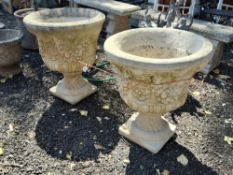 A PAIR OF LARGE WEATHERED CONCRETE GARDEN URNS, with a fruiting swag to facet, on a square base,
