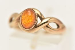 A 9CT YELLOW GOLD GEM SET RING, oval cabochon composite amber collet set in yellow gold,