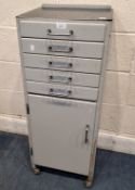 A GREY PAINTED DENTIST / MEDICAL CABINET, with five drawers over a single cupboard door, raised on
