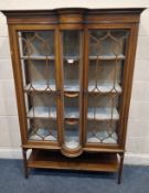 AN EDWARDIAN MAHOGANY CHINA CABINET, the two glass doors enclosing three shelves, flanking a