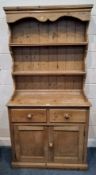 A PINE DRESSER, the three-tier plate rack atop a base with two drawers over double cupboard doors