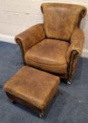 A TANNED LEATHER ARMCHAIR, with scrolled armrests, raised on square tapered legs, along with a