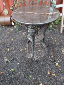 A CAST IRON PUB TABLE with male mask bosses on the legs and a black marble 61cm diameter top