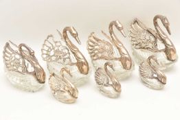 SEVEN SILVER AND WHITE METAL WINGED GLASS SWAN SALTS, to include three large, one medium and three