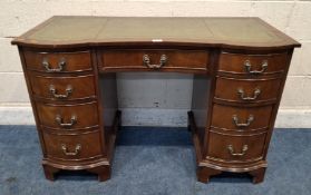 A REPRODUCTION MAHOGANY DOUBLE BOW FRONT DESK, with a green leather writing surface, fitted with