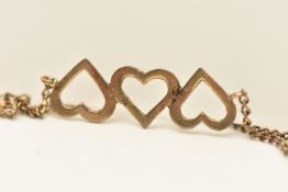 A YELLOW METAL OPEN WORK HEART BRACELET, designed as three open work hearts, on a trace chain fitted
