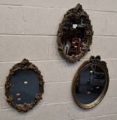 A PAIR OF GILT RESIN OVAL WALL MIRRORS, with a foliate frame, along with another mirror Dimensions: