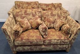 A RED AND GOLD FOLIATE UPHOLSTERED TWO-PIECE LOUNGE SUITE, comprising a large two-seater sofa and