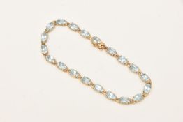 A 9CT YELLOW GOLD GEM SET LINE BRACELET, oval cut light blue topaz, prong set in yellow gold, fitted