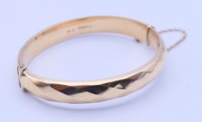 A 9 ct gold bangle form bracelet. 1 cm high, 6 cm internal diameter. 13.5 grammes.