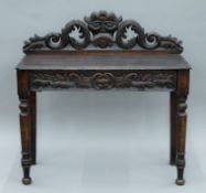 A Victorian carved oak Greenman side table. 106 cm wide.