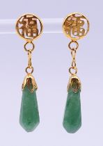 A pair of Chinese unmarked yellow metal mounted jade earrings. 4 cm high.