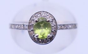 A 10 K white gold, diamond and peridot ring. Ring size K/L. 1.6 grammes total weight.
