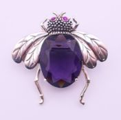 A silver bee form brooch with purple stone body and pink stone inset eyes. 3.5 cm high.