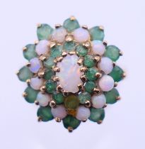 A 9 ct gold, opal and emerald cluster ring. Ring size O/P. 4.9 grammes total weight.