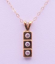 A 9 ct gold three-stone pendant on a 9 K gold chain. Pendant 1.