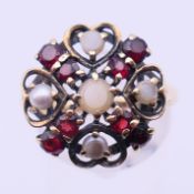 A 9 ct gold, garnet, moonstone and seed pearl ring. Ring size Q. 3.8 grammes total weight.