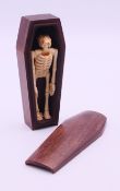 A wood coffin enclosing a bone skeleton. Coffin 12 cm long.