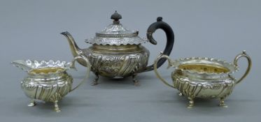A silver embossed three-piece tea set. The teapot 13 cm high. 673.1 grammes total weight.