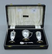 A cased silver three-piece cruet set. The case 23.5 cm wide. 181.5 grammes.