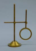 A brass magnifying glass on stand. 25 cm high.