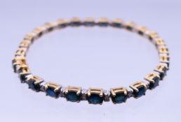 A 14k gold sapphire and diamond tennis bracelet. 18 cm long, 4 mm high. 13.1 grammes total weight.
