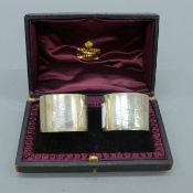 A cased pair of silver napkin rings. The case 13.5 cm wide. 60 grammes.