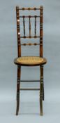 A Victorian cane-seated child's correction chair. 104 cm high.