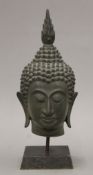 An antique bronze Buddha head on stand. 30.5 cm high overall.