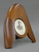 A wood photograph frame made from the tip of a WWI propeller containing a photograph of a young