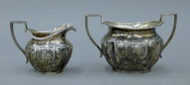 An embossed silver cream jug and silver sugar bowl. The latter 16 cm wide. 351.7 grammes.