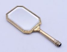 A miniature gilt metal hand mirror, the handle inscribed PAM. 9.5 cm high.