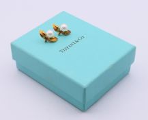 A boxed pair of 18 ct gold Tiffany pearl and leaf earrings. 2 cm wide x 1.5 cm high.
