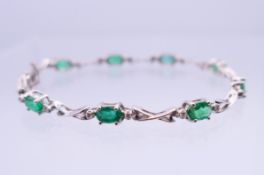 A 14K white gold, diamond and emerald bracelet. 18 cm long. 7.7 grammes total weight.