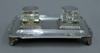 A silver desk stand. 23.5 cm wide. 757 grammes excluding inkwells.