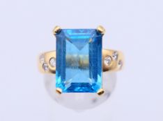 An 18 ct yellow gold and 5 carat emerald cut aquamarine ring with three diamonds to each shoulder.