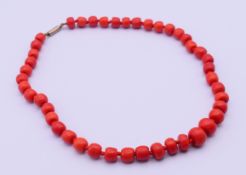 A coral bead necklace. 44 cm long, central bead 1 x 1.2 cm.
