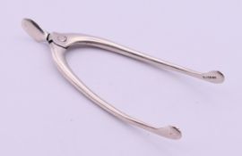 A pair of silver wishbone tongs. 9 cm high.