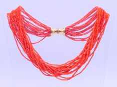 A coral multi-strand beaded necklace with an 18 ct gold clasp. 46 cm long. 68.