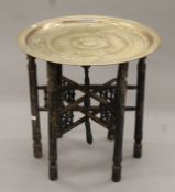 An Eastern brass-topped folding table. 58 cm diameter.