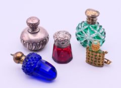 A silver scent bottle, a silver topped red glass scent bottle and three glass scent bottles.