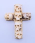 A bone cross decorated with skulls. 7 cm high.