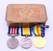 A 1914 Princess Mary Christmas tin containing three replica WWI medals.