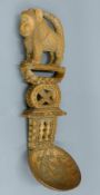 A large African spoon with monkey terminal, with a carved stool below,