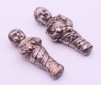 A pair of white metal scent bottles formed as children. 7.5 cm high and 7 cm high.