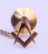A 9 ct gold Freemasons' tie tack with safety chain. 1.2 cm high. 0.4 grammes of gold.