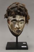 A vintage African mask of a male covered with white,