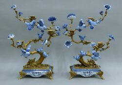A pair of blue and white porcelain and gilt metal bird in tree-form candelabra. Each 52 cm high.